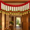 Red and White Artificial Flower Door Toran with Gold Bells Red and white artificial flower toran with gold bells displayed above a doorway