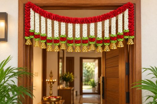 Red and white artificial flower toran with gold bells displayed above a doorway